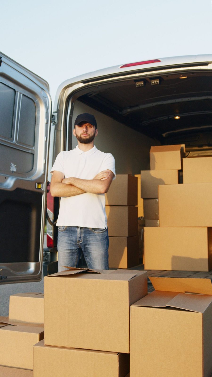 A driver standing beside his van loaded with boxes