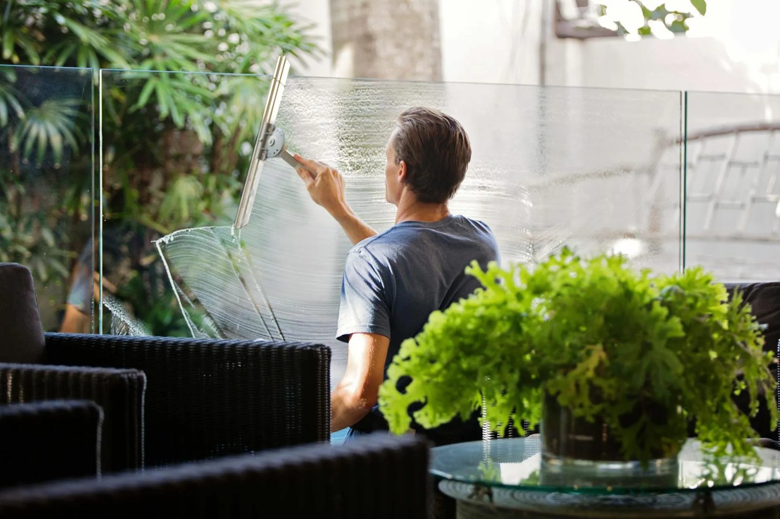 A cleaner wiping a window in a bright office