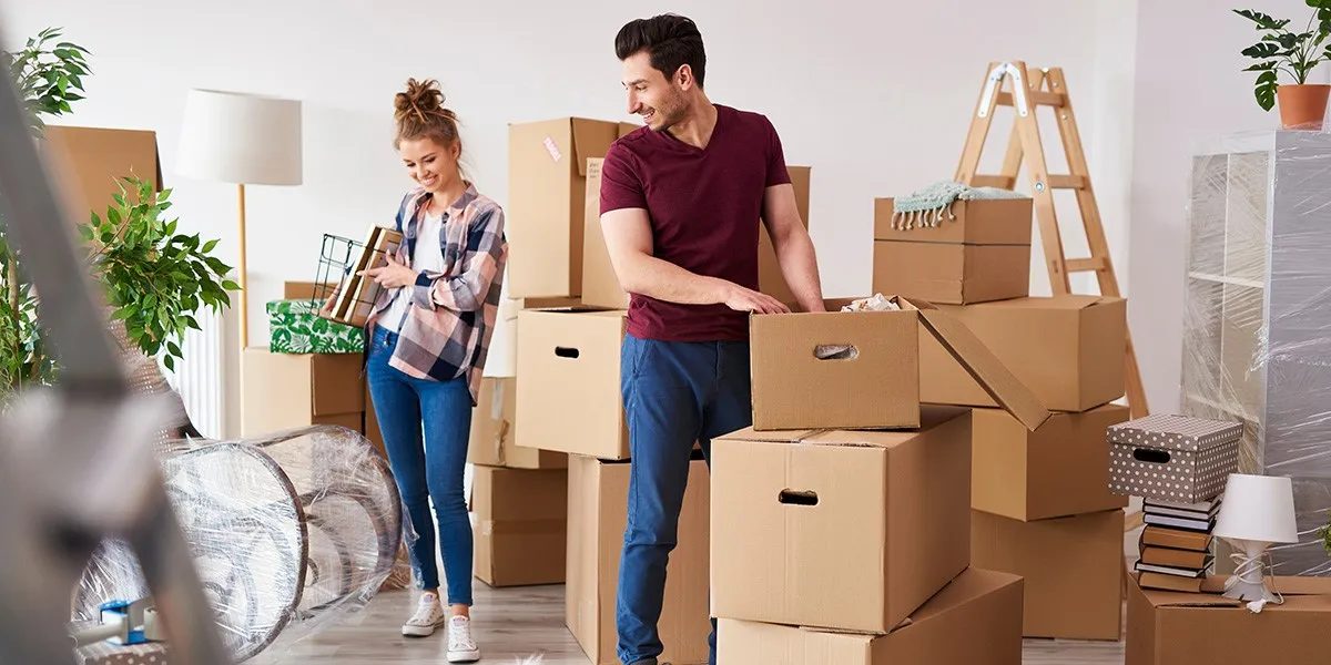A couple carrying boxes while moving their belongings